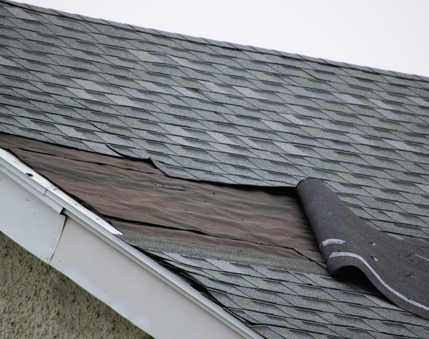 Roofing contractor inspecting a wind-lifted eave in Columbus, NE