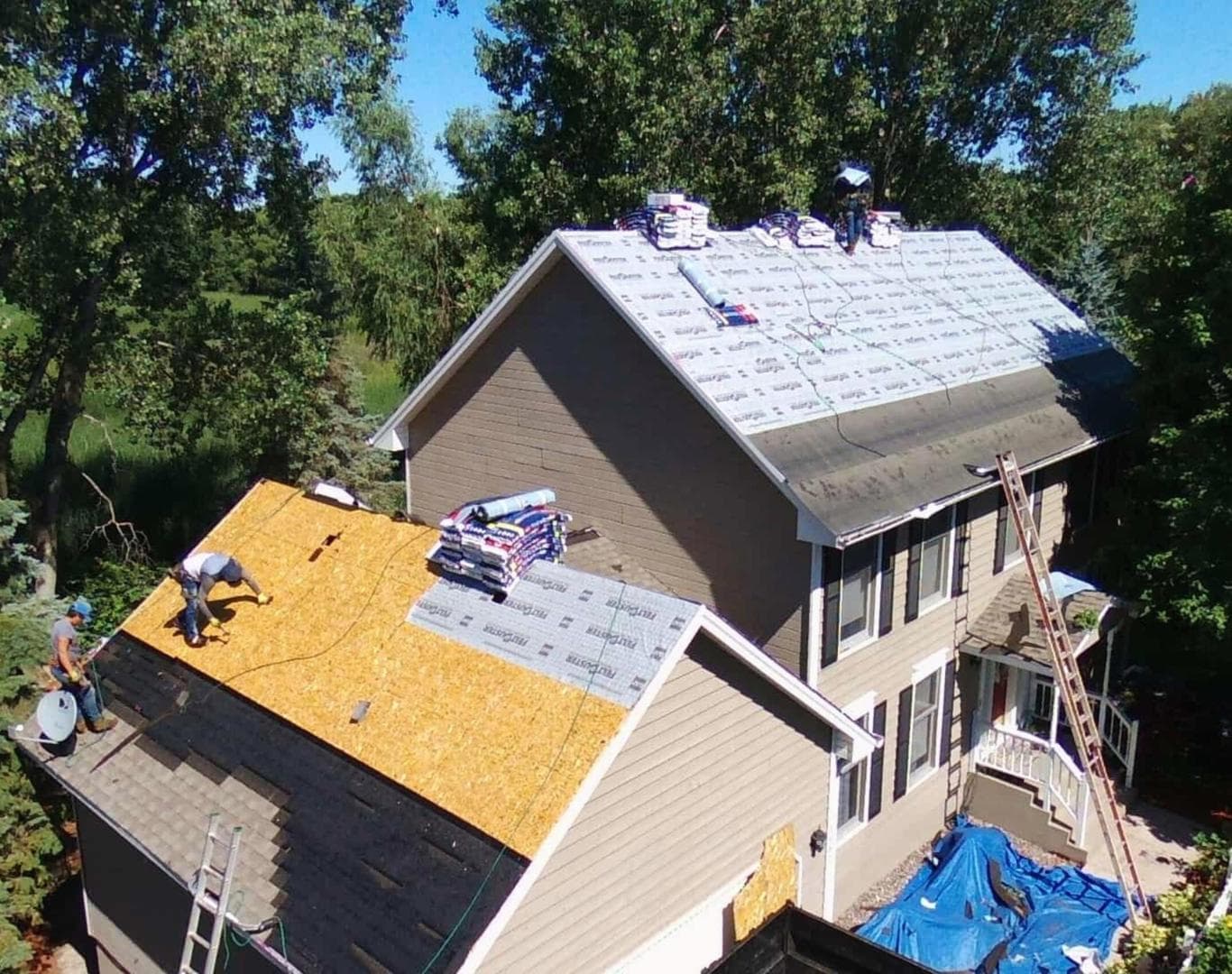 Aerial view of a permitted roof tear-off with exposed decking and staged shingle bundles