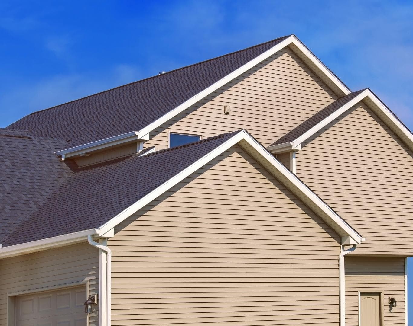 Tan vinyl siding gables and an asphalt shingle roof on a two-story home